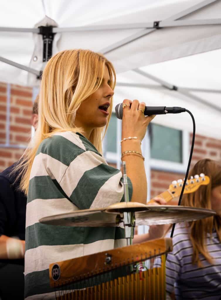 En elev synger i mirkofon til en udendørs koncert ved sommereventet på Nøvlingskov Efterskole